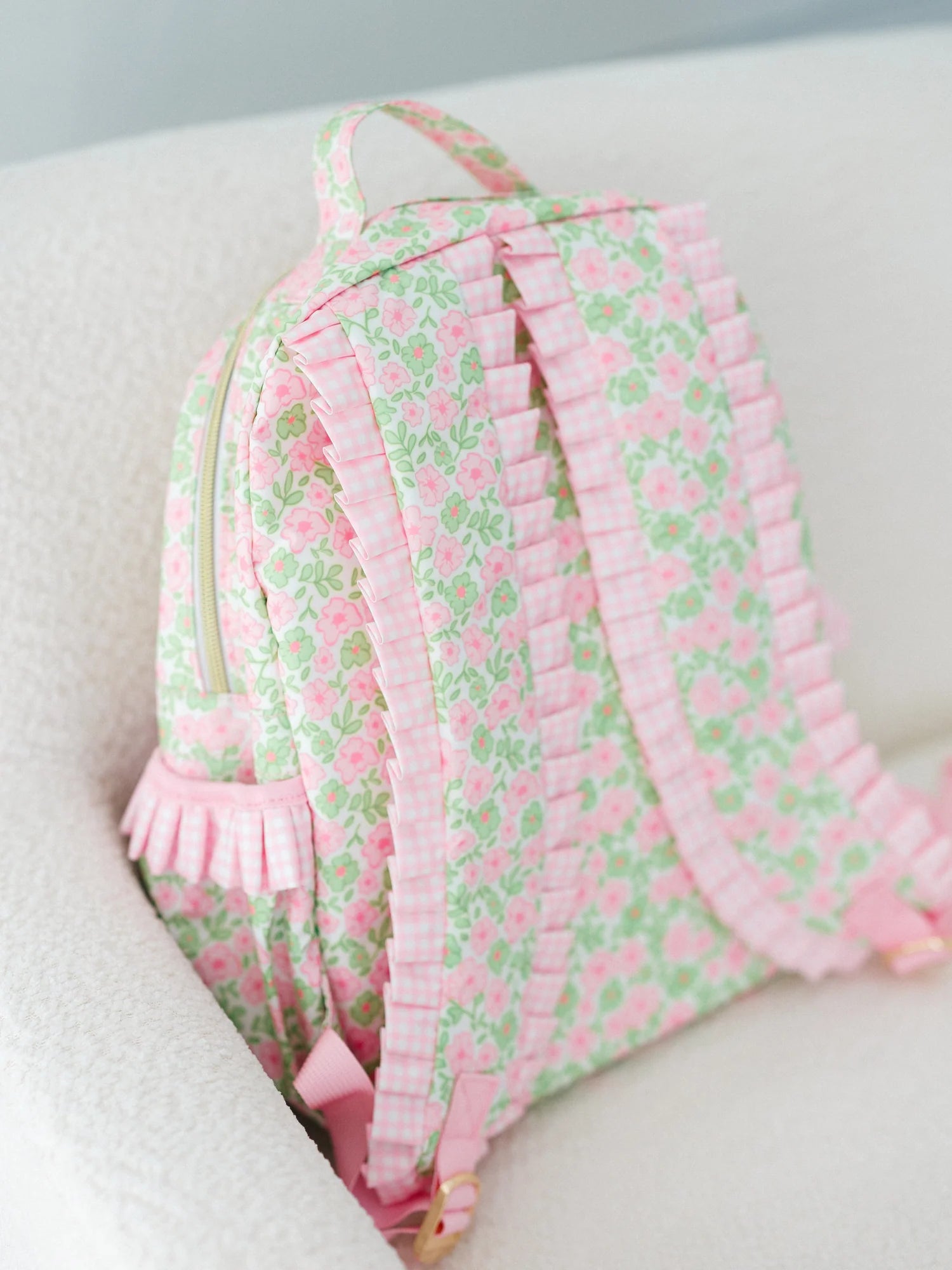 Floral patterned backpack with ruffles on a light background