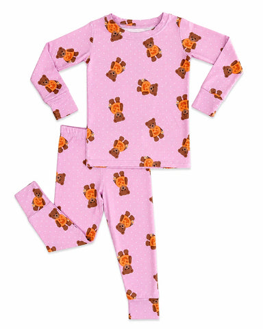 A two-piece children's pajama set featuring a long-sleeve top and matching pants in light pink with a repeating pattern of brown teddy bears holding orange buckets, shown on a plain white background.