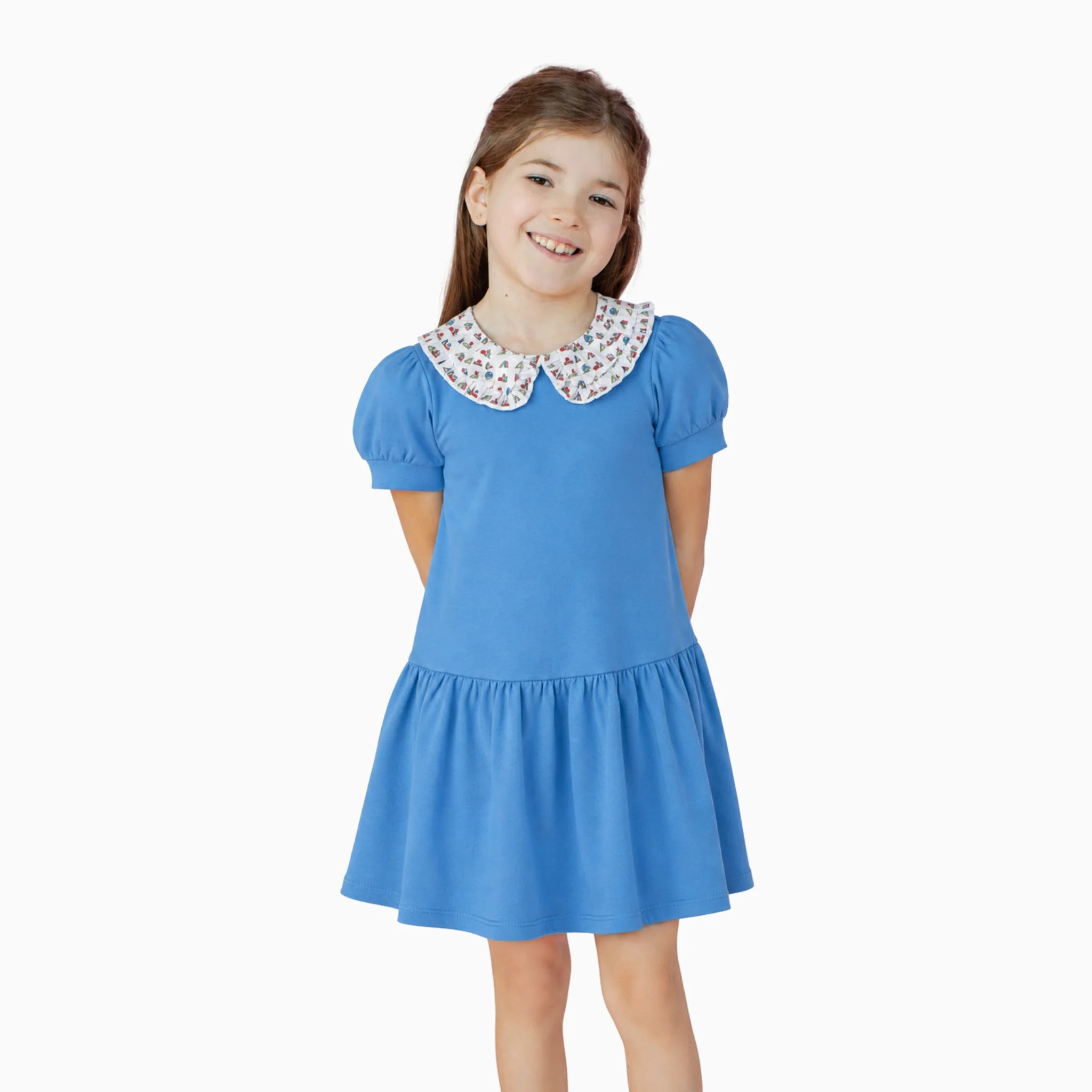 Young girl wearing a blue dress with a patterned collar on a white background