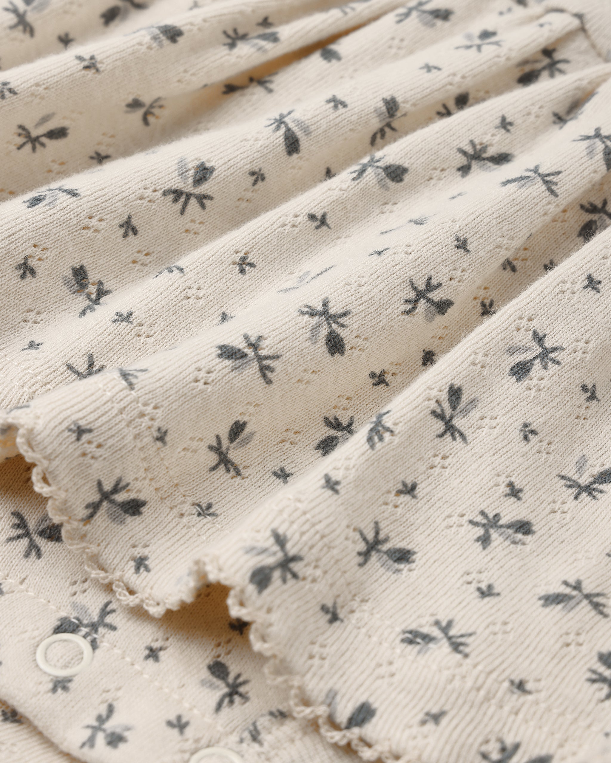 A close up of a pointelle natural fabric with a small floral print.