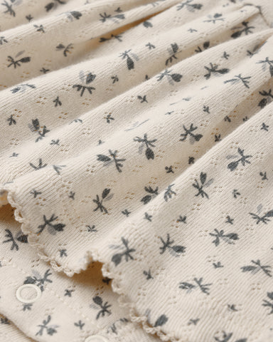 A close up of a pointelle natural fabric with a small floral print.