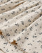 A close up of a pointelle natural fabric with a small floral print.