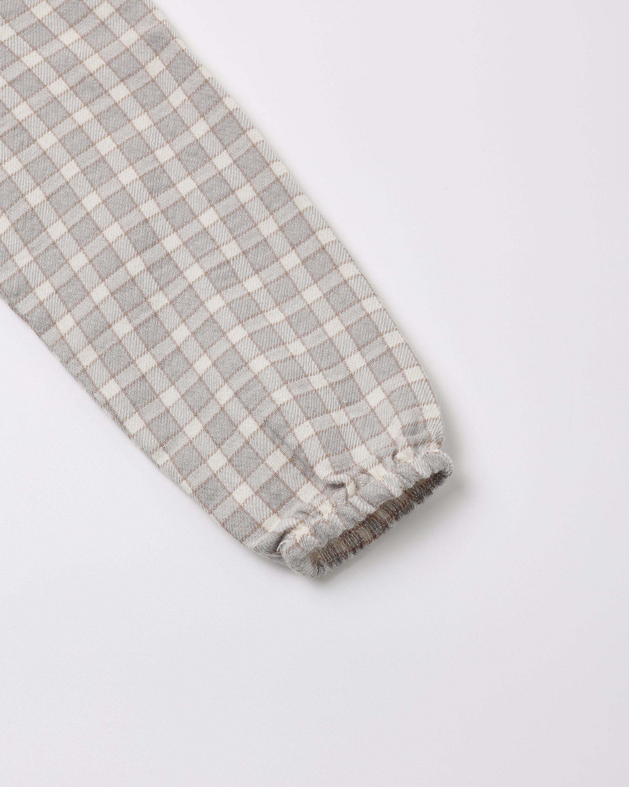 Close-up of a blue gingham fabric sleeve with a gathered elastic cuff, shown on a light gray background.