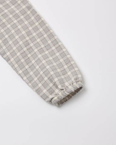 Close-up of a blue gingham fabric sleeve with a gathered elastic cuff, shown on a light gray background.