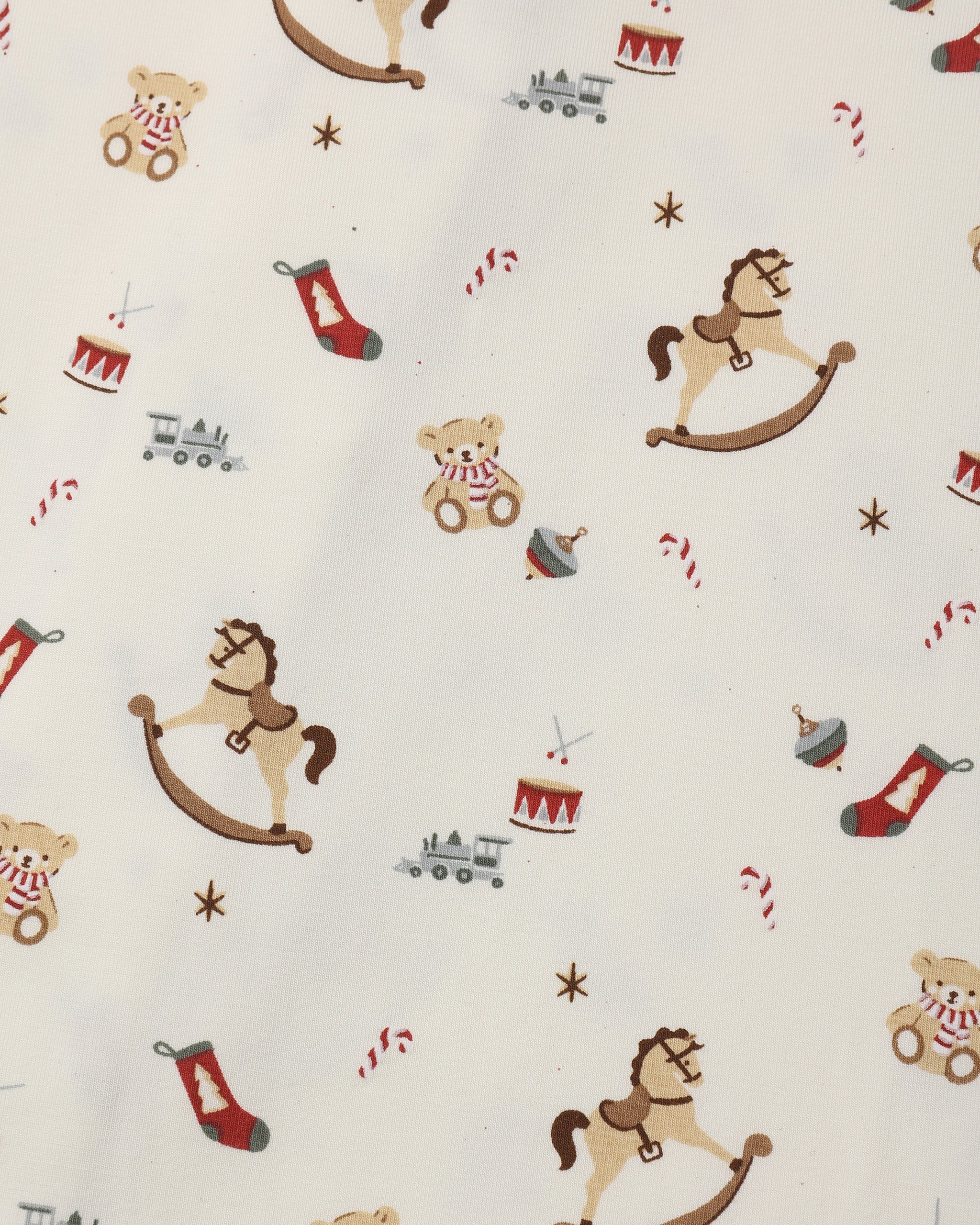 A close-up of a fabric pattern featuring Christmas toys and holiday motifs, including rocking horses, teddy bears, stockings, candy canes, and toy trains on an off-white background.