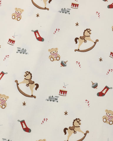 A close-up of a fabric pattern featuring Christmas toys and holiday motifs, including rocking horses, teddy bears, stockings, candy canes, and toy trains on an off-white background.