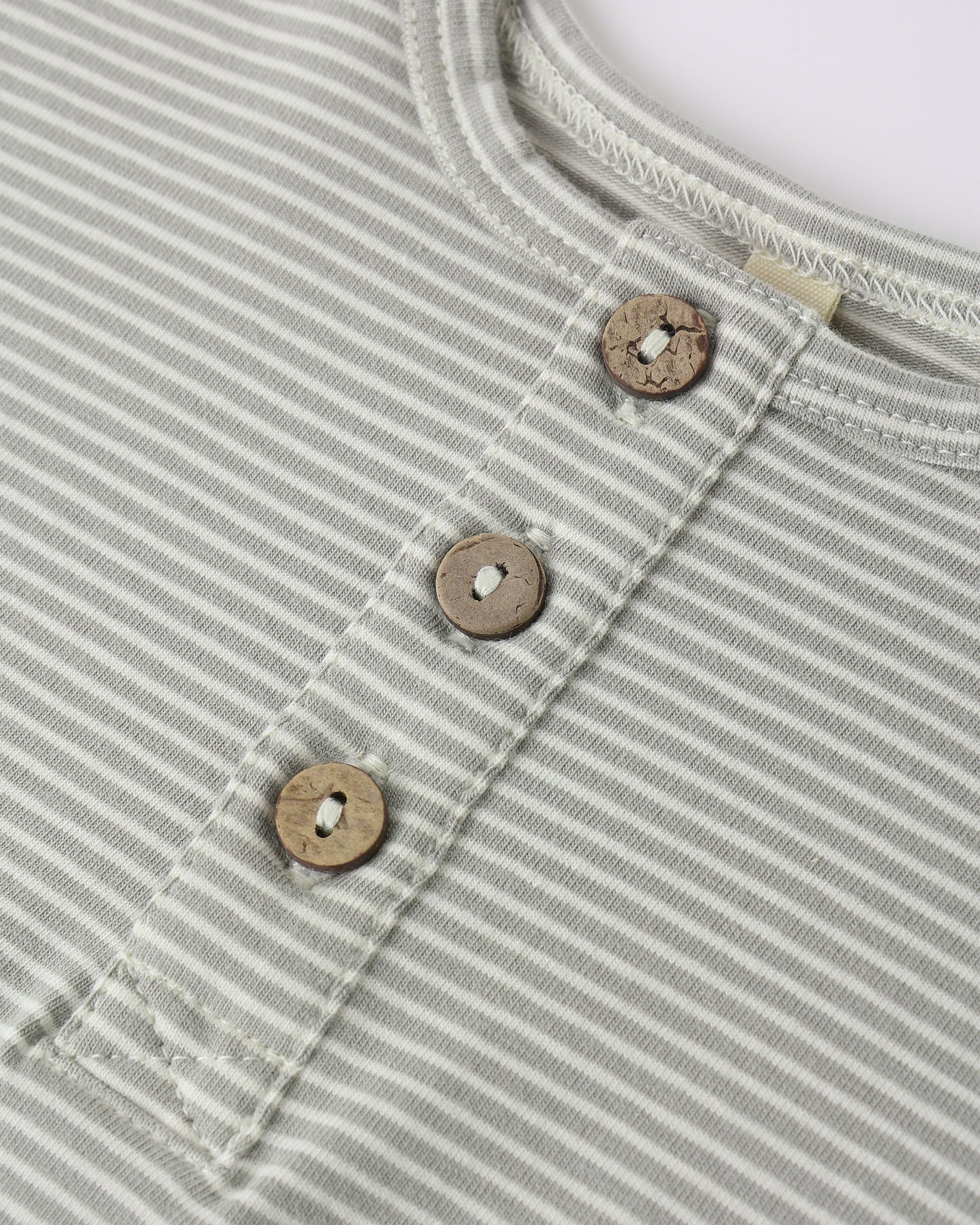 Close-up of a light green striped romper with wooden buttons on a white background
