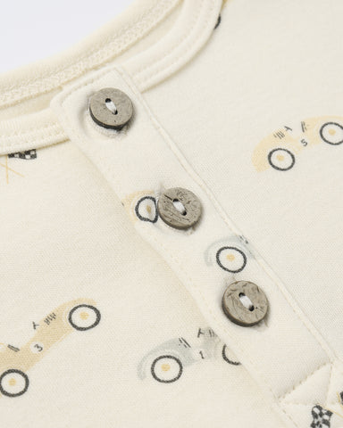 Close-up of a cream-colored fabric with button details and small vehicle prints.