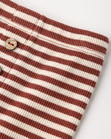 Close-up of a ribbed knit garment with horizontal rust red and cream stripes, featuring a wooden button closure, on a light gray background.