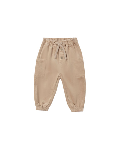 A pair of beige jogger pants for toddlers, featuring an elastic waistband with a drawstring, button details, and side pockets, shown against a plain white background.