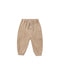 A pair of beige jogger pants for toddlers, featuring an elastic waistband with a drawstring, button details, and side pockets, shown against a plain white background.