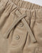 Close-up of beige corduroy pants showing the elastic waistband, braided drawstring, and two matching buttons.