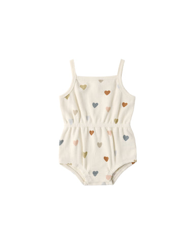 cream romper with colorful heart patterns on a white background