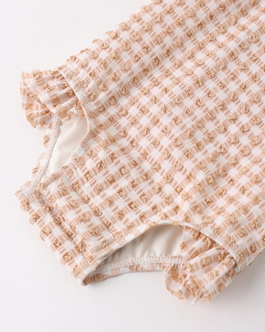 Folded fabric with a melon colored gingham pattern on a white background