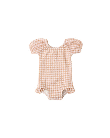 Melon colored gingham baby swimsuit with ruffled sleeves and bottom on a white background