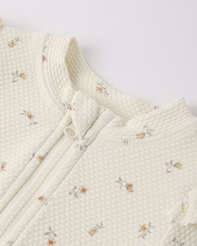 Close-up of a textured white fabric with floral patterns on a light gray background
