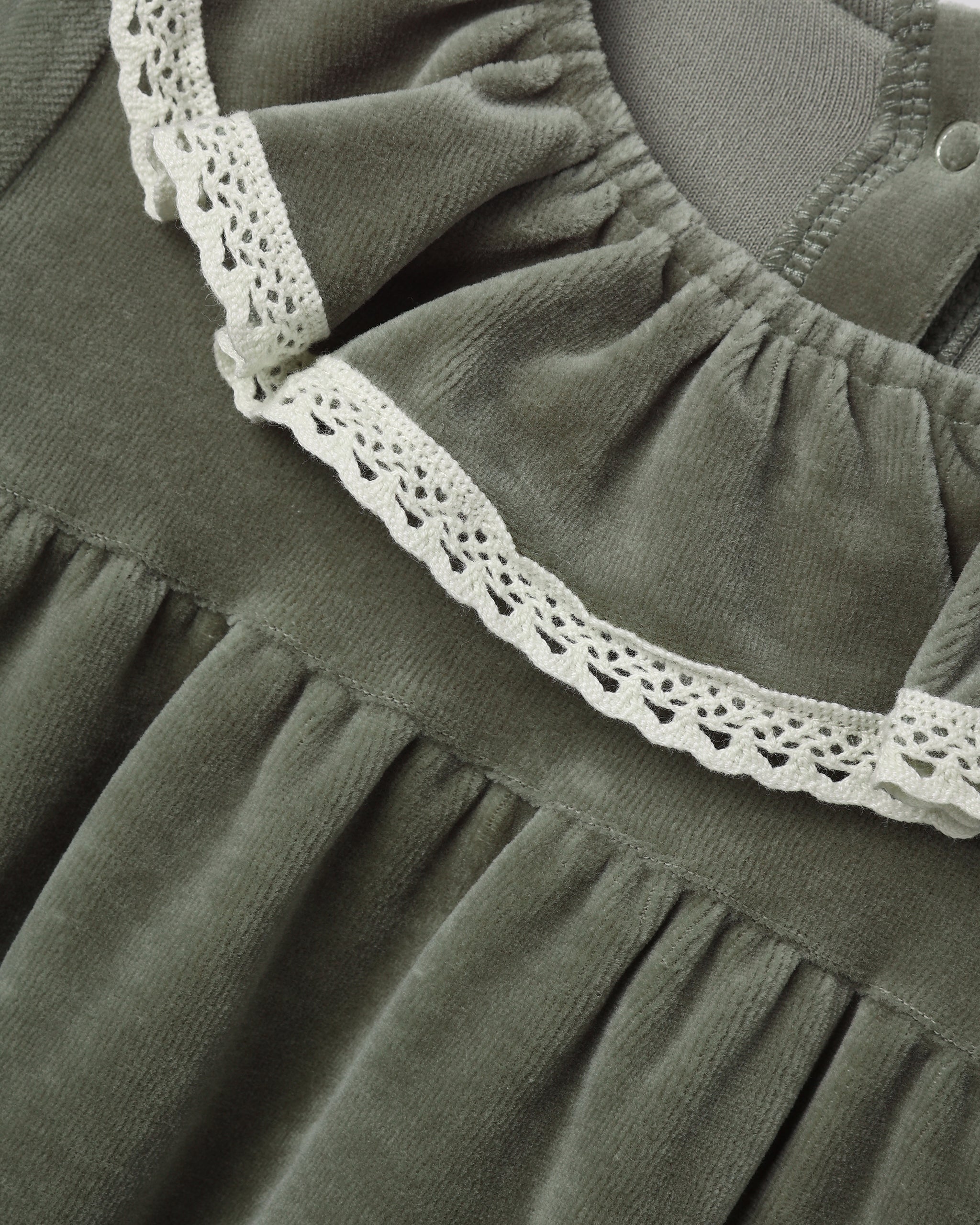 Close-up of a dark olive green dress or nightgown with a gathered neckline and white crochet lace trim.