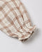 A close-up of a soft cotton fabric sleeve or cuff with a beige and off-white gingham check pattern and a gathered elastic ruffle at the end, shown on a light gray background.