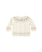 A cream-colored knit baby sweater with long sleeves, featuring a decorative yoke pattern of gray trees and a beige geometric border on the cuffs and hem.