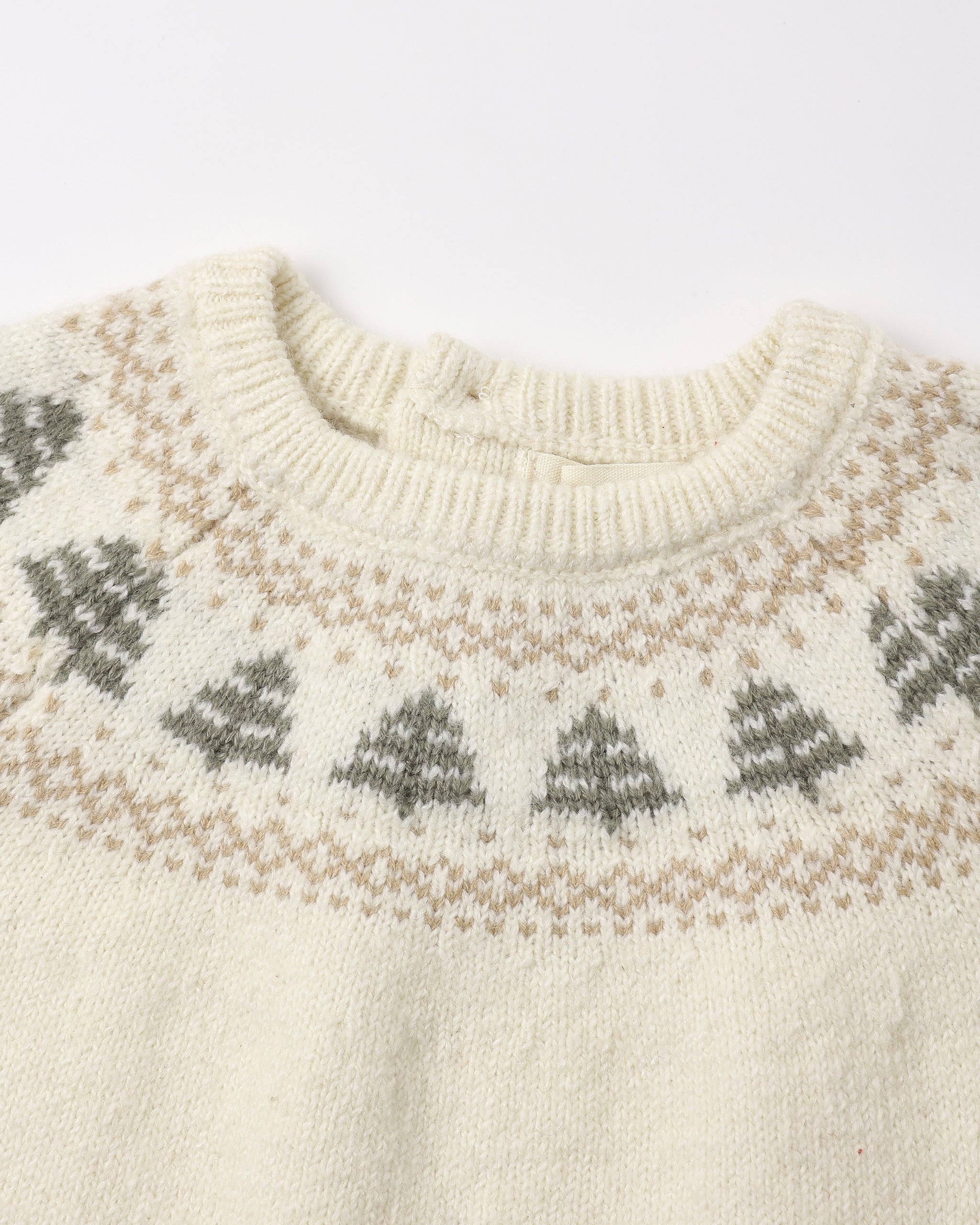 Close-up of a cream-colored knit sweater with a classic Fair Isle pattern featuring gray and tan Christmas trees and geometric borders around the crew neck.