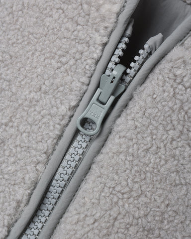 Close-up of a light gray fleece jacket with a matching gray zipper and pull tab.