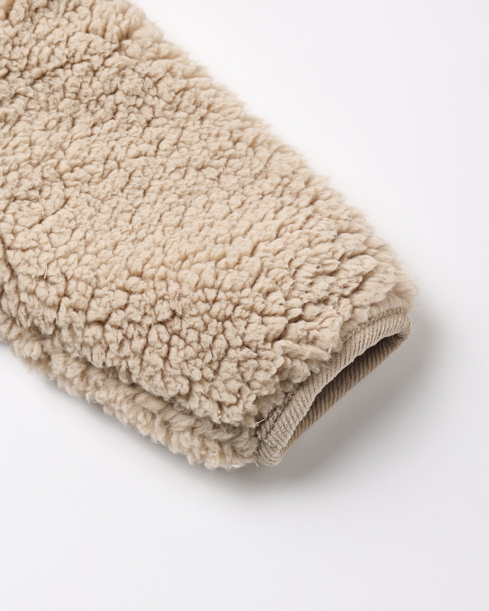 Close-up of a beige sherpa fleece fabric sleeve or cuff with a ribbed knit trim, photographed on a clean white background.