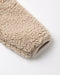 Close-up of a beige sherpa fleece fabric sleeve or cuff with a ribbed knit trim, photographed on a clean white background.