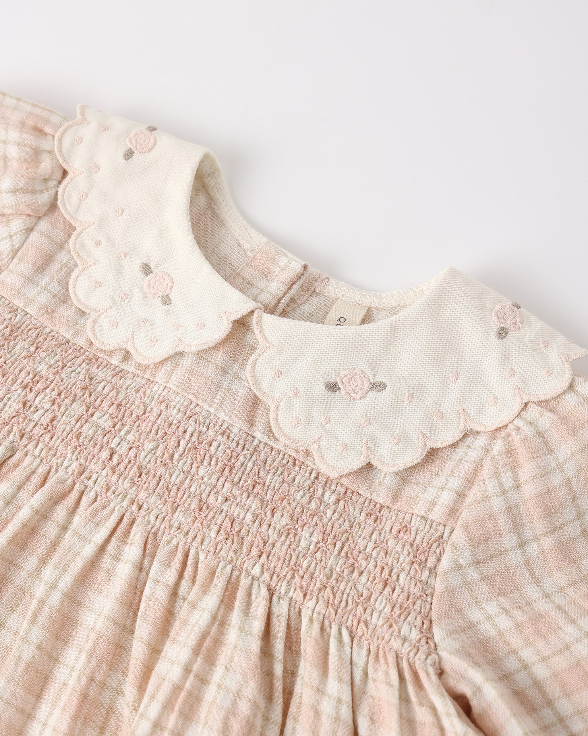 Pink checkered dress with scalloped collar on a light gray background