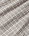 A close-up of a plaid fabric with a gray and off-white checkered pattern and thin brown intersecting lines.