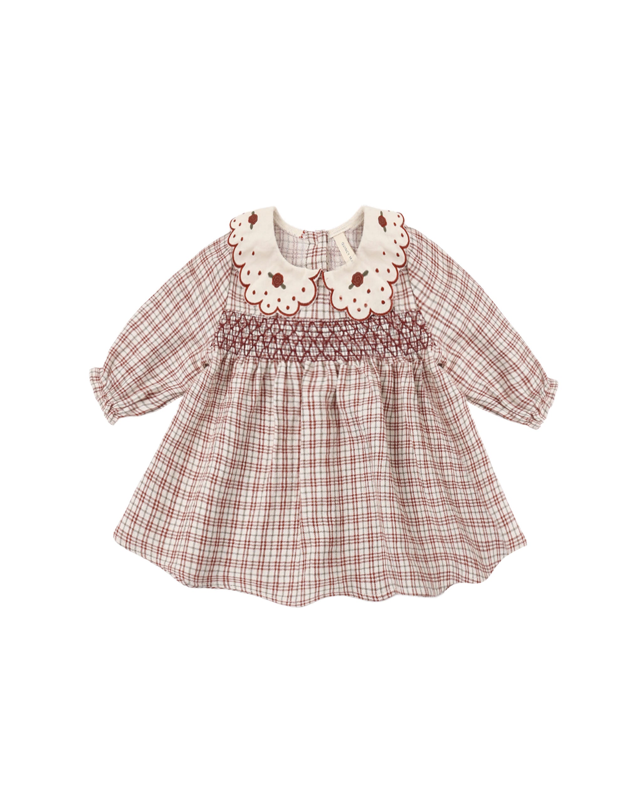 A baby girl's long-sleeve smocked dress in a brown and beige plaid pattern, featuring a cream-colored embroidered Peter Pan collar with brown floral details.