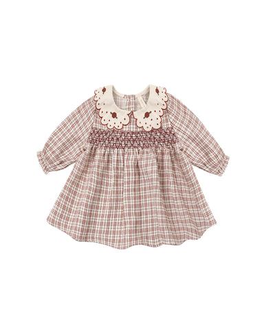 A baby girl's long-sleeve smocked dress in a brown and beige plaid pattern, featuring a cream-colored embroidered Peter Pan collar with brown floral details.