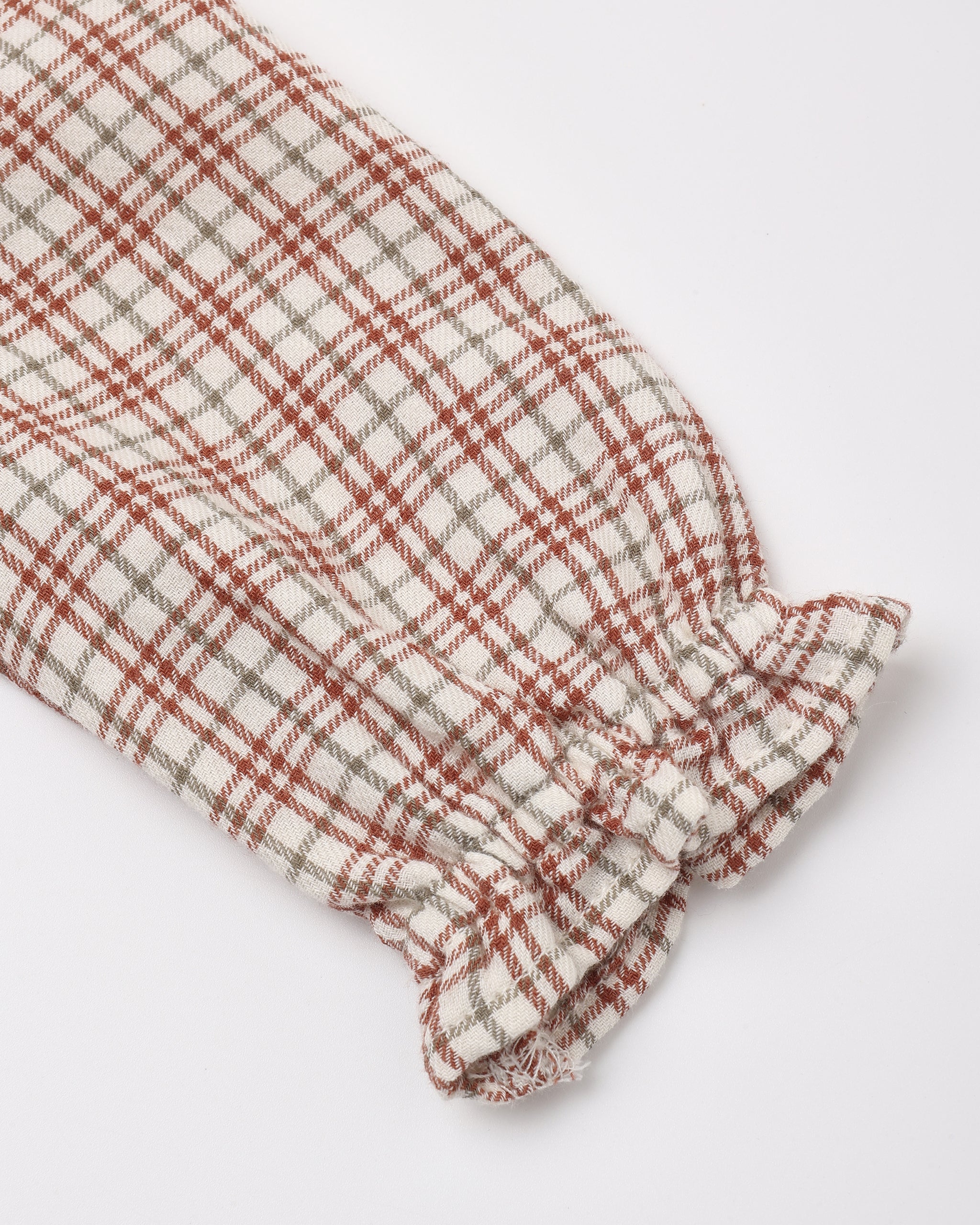 A close-up of a plaid fabric sleeve or cuff with gathered ruffles at one end, shown on a clean white background.