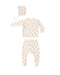 A three-piece baby clothing set laid flat on a white background, including a long-sleeve footed sleeper, matching pants, and a bonnet. The set is cream-colored with a small red dog print pattern.