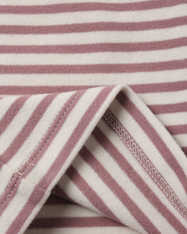Close-up of a striped fabric with alternating dusty rose and off-white horizontal stripes, showing a folded corner with stitched edges.