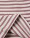Close-up of a striped fabric with alternating dusty rose and off-white horizontal stripes, showing a folded corner with stitched edges.