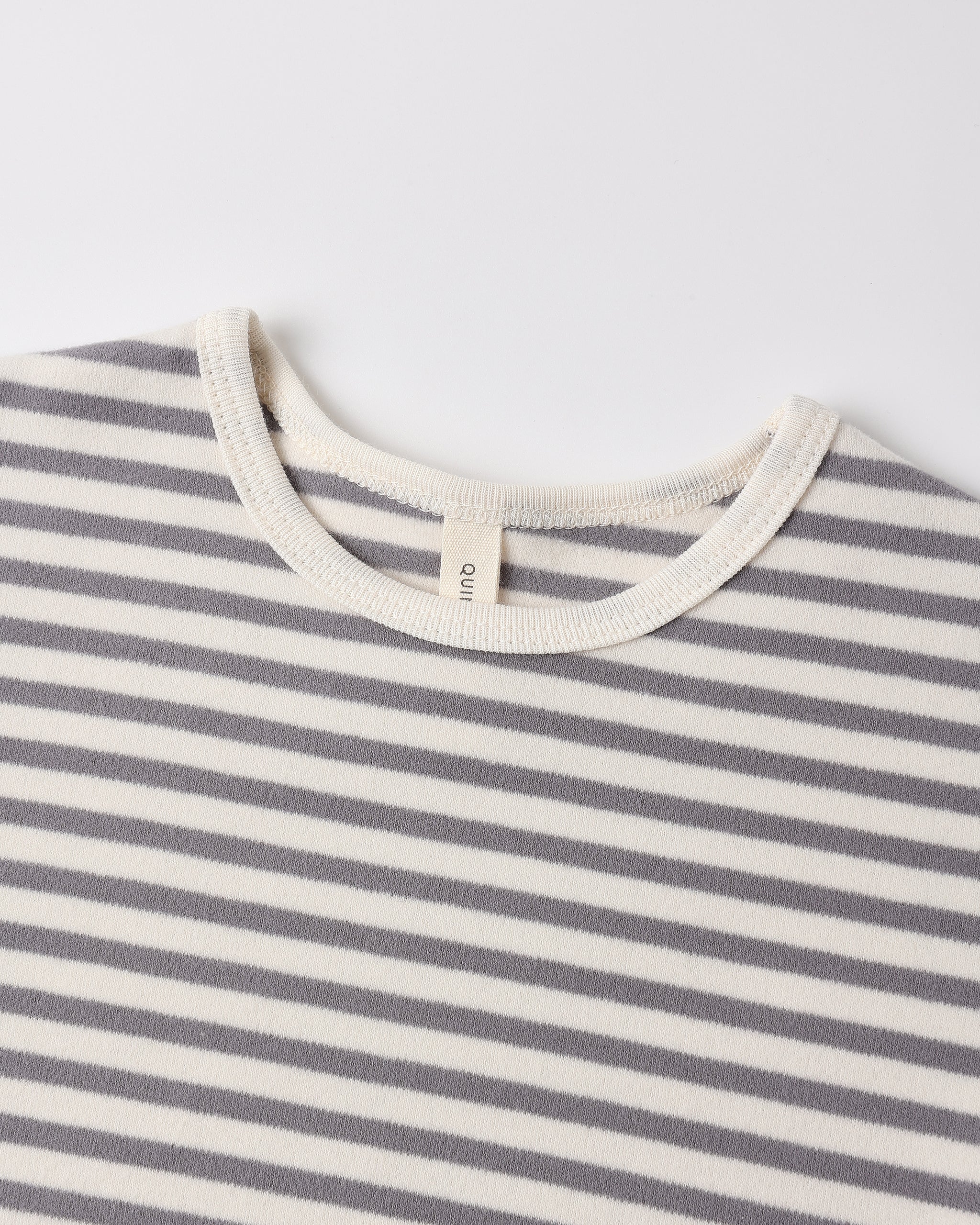 Close-up of a striped knit top with alternating gray and off-white horizontal stripes, featuring a cream ribbed crew neck and a small interior neck label reading 'GANT'.