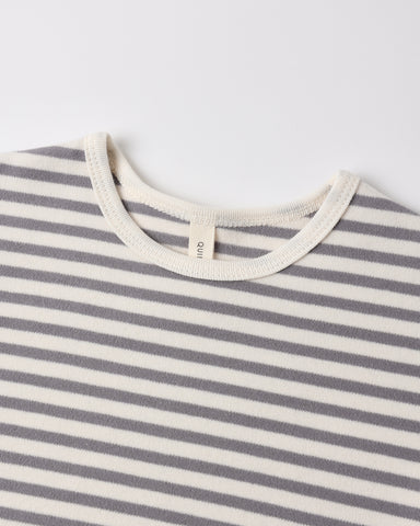 Close-up of a striped knit top with alternating gray and off-white horizontal stripes, featuring a cream ribbed crew neck and a small interior neck label reading 'GANT'.