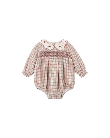 A baby long-sleeve romper with a brown and beige plaid pattern, featuring a smocked chest, a cream lace collar with embroidered flowers, and a ruffled leg opening.