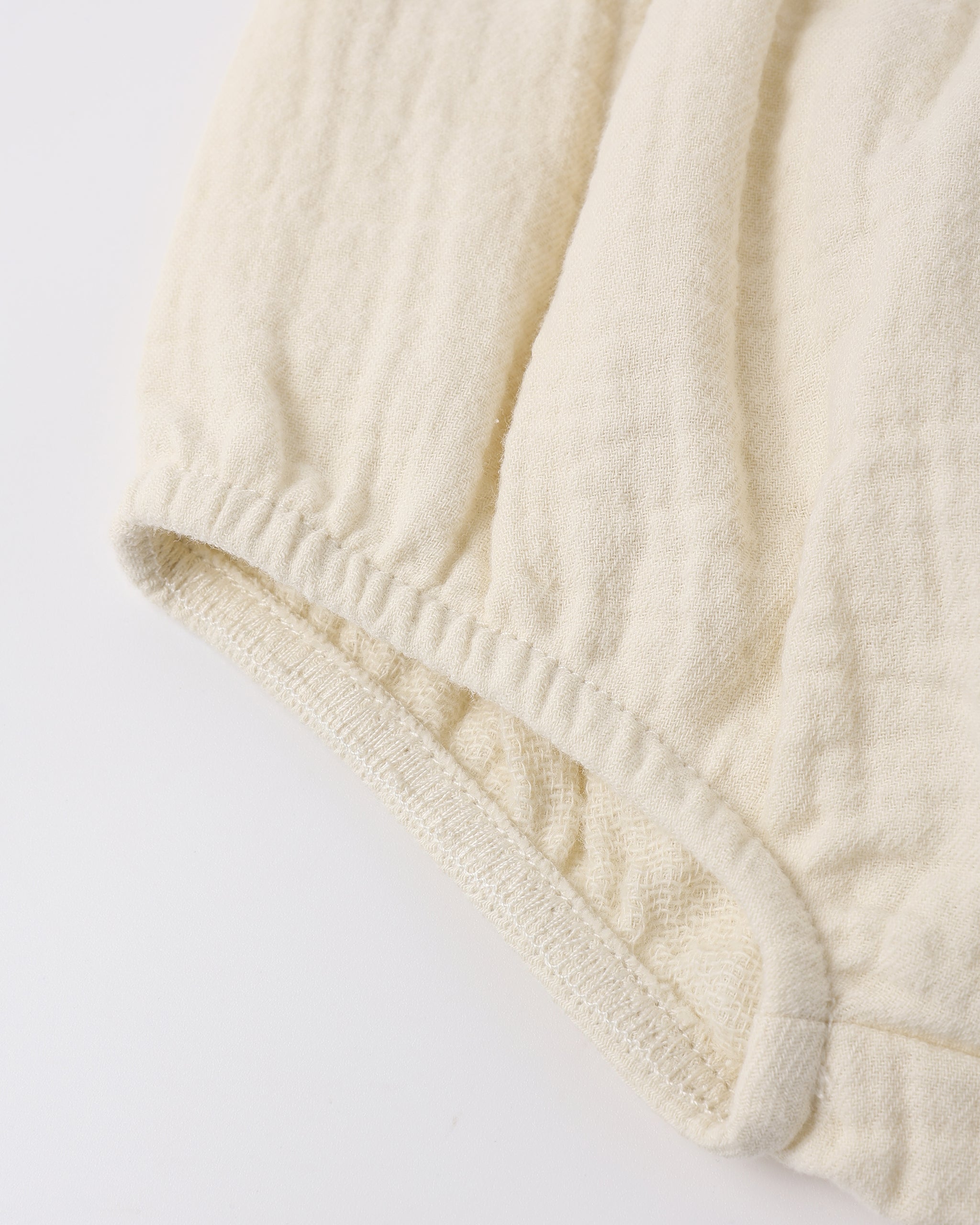 Close-up of a textured cream-colored fabric on a light gray background