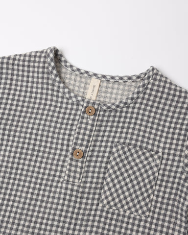 A close up of the woven black gingham fabric with a front two-button placket and chest pocket