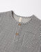 A close up of the woven black gingham fabric with a front two-button placket and chest pocket