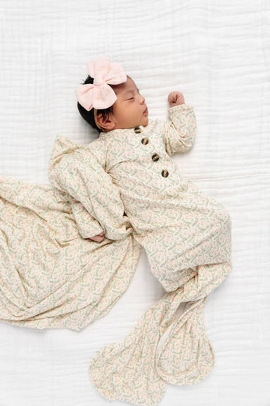 Newborn baby wrapped in a textured blanket with a pink bow on a white background