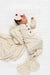 Newborn baby wrapped in a textured blanket with a pink bow on a white background