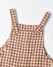 Brown and cream gingham check pinafore overalls with adjustable straps and wooden buttons, shown on a clean white background.