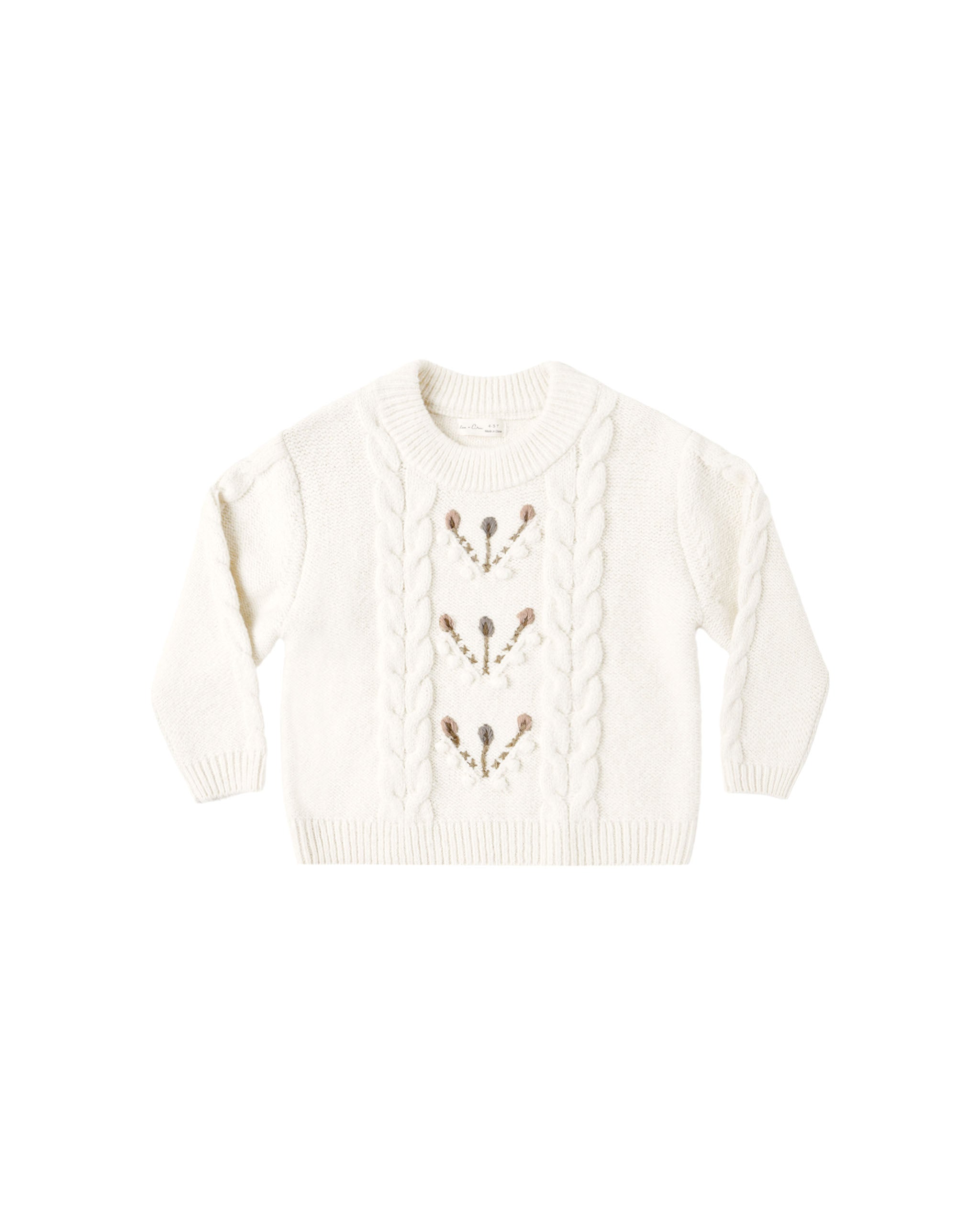 A natural colored sweater with a floral design down the center shown on a white background