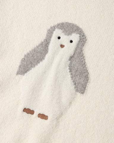 A close-up of a soft knit fabric featuring a penguin motif in white and gray with small brown accents.