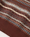 Close-up of a knit sweater corner showing a brown ribbed cuff and a Fair Isle style pattern with horizontal stripes in brown, cream, and dark gray.