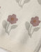 Close-up of a cream knit fabric with a repeating floral pattern featuring dusty pink flowers and muted green leaves.