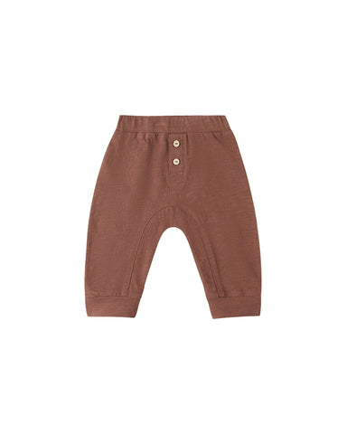 A pair of toddler knit pants in a warm terracotta brown color, featuring a buttoned henley waistband with two small buttons and a curved leg design, shown on a plain white background.