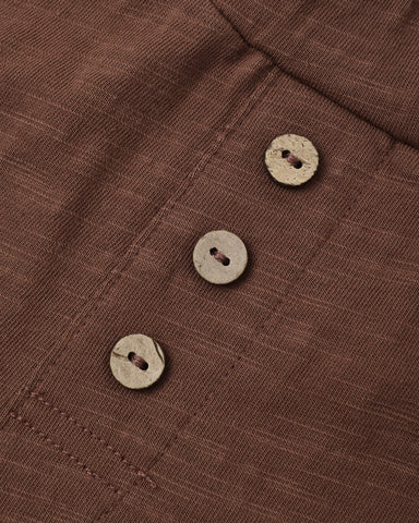 Close-up of a brown textured fabric garment with three round natural wood buttons aligned vertically.